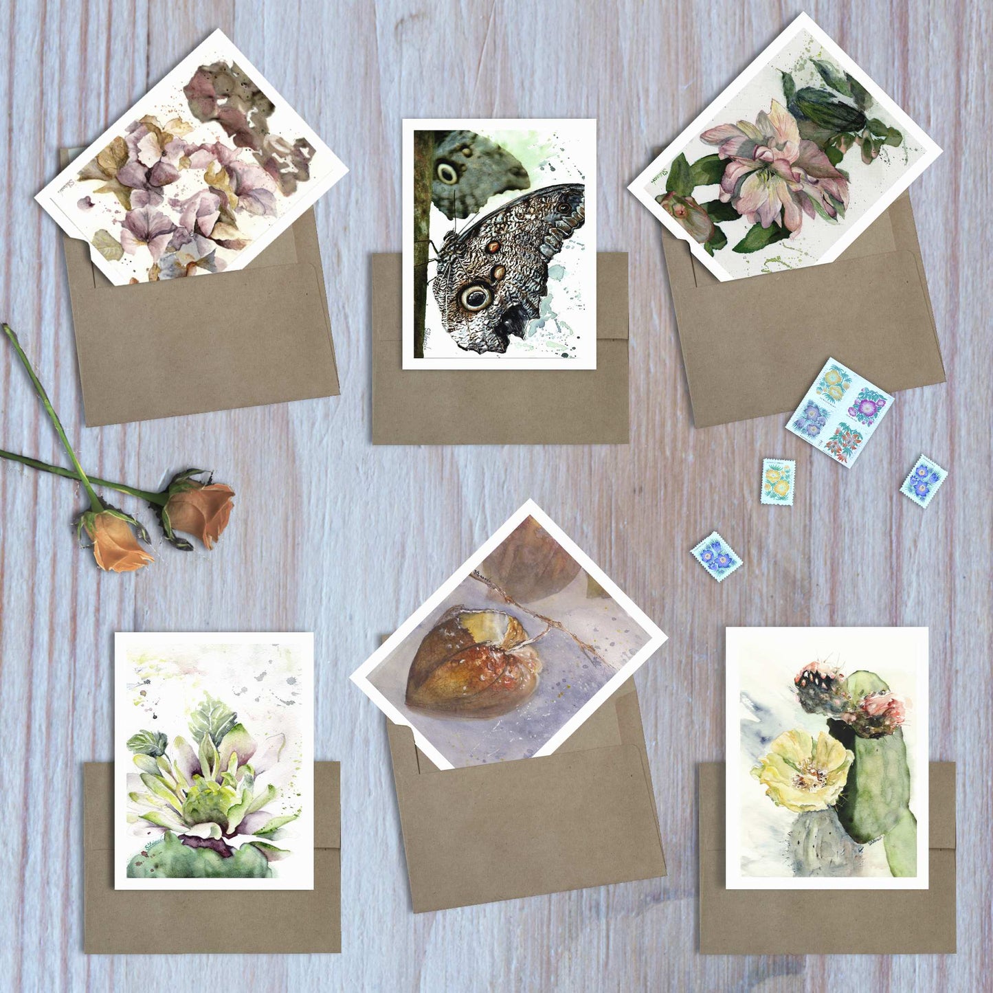 Set of 6 assorted watercolor art greeting cards from the Earthbound collection, fanned out on envelopes on wooden surface.