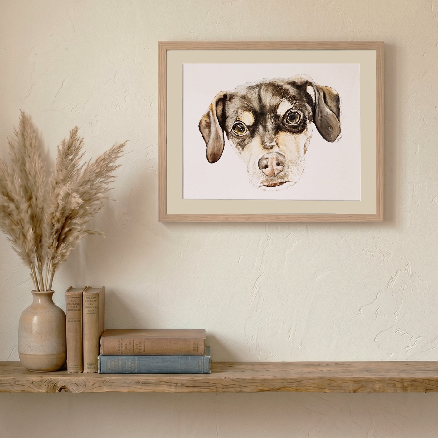 An original artwork print by Silvana Varriale for varsee, displayed in a light wood frame. The portrait is staged on a rustic wooden shelf with pampas grass and books, showcasing a warm, organic home decor aesthetic.