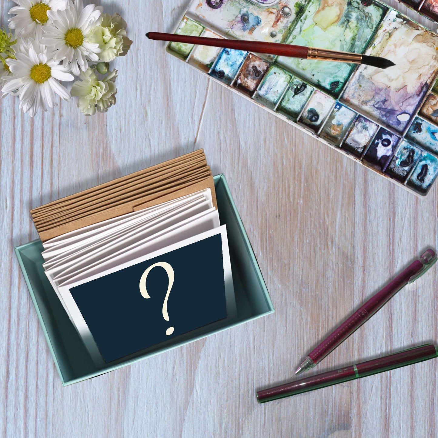 An unlidded box containing question marked mystery cards and their envelopes.