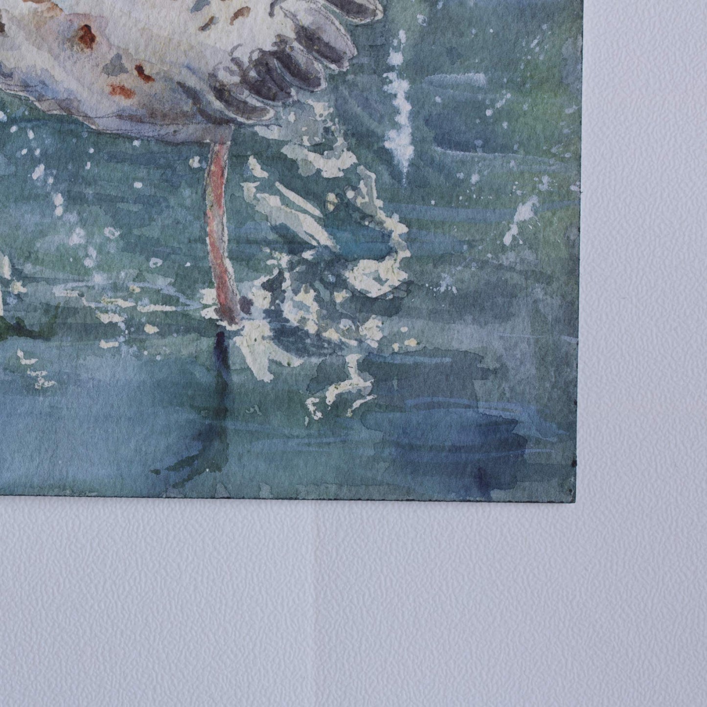 Close-up of the lower right corner of the original watercolor painting Wingspan Airlines, showing the seagull's leg with water splashes against deep green and blue tones with watercolor splatters, on rough-textured cotton paper, by artist Silvana Varriale of VARsee Art.