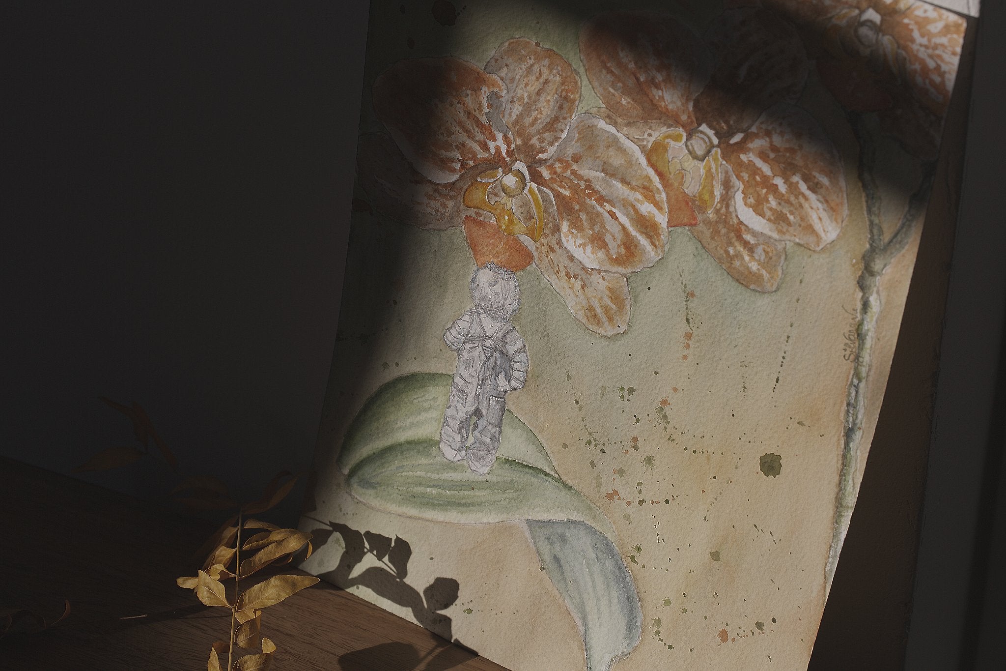 Original watercolor painting Three Sisters by Silvana Varriale leaning against a wall, lit by a ray of light with darkness on either side, a yellow leafy branch casting its shadow across the painting, part of the natureAWE collection | VARsee art studio