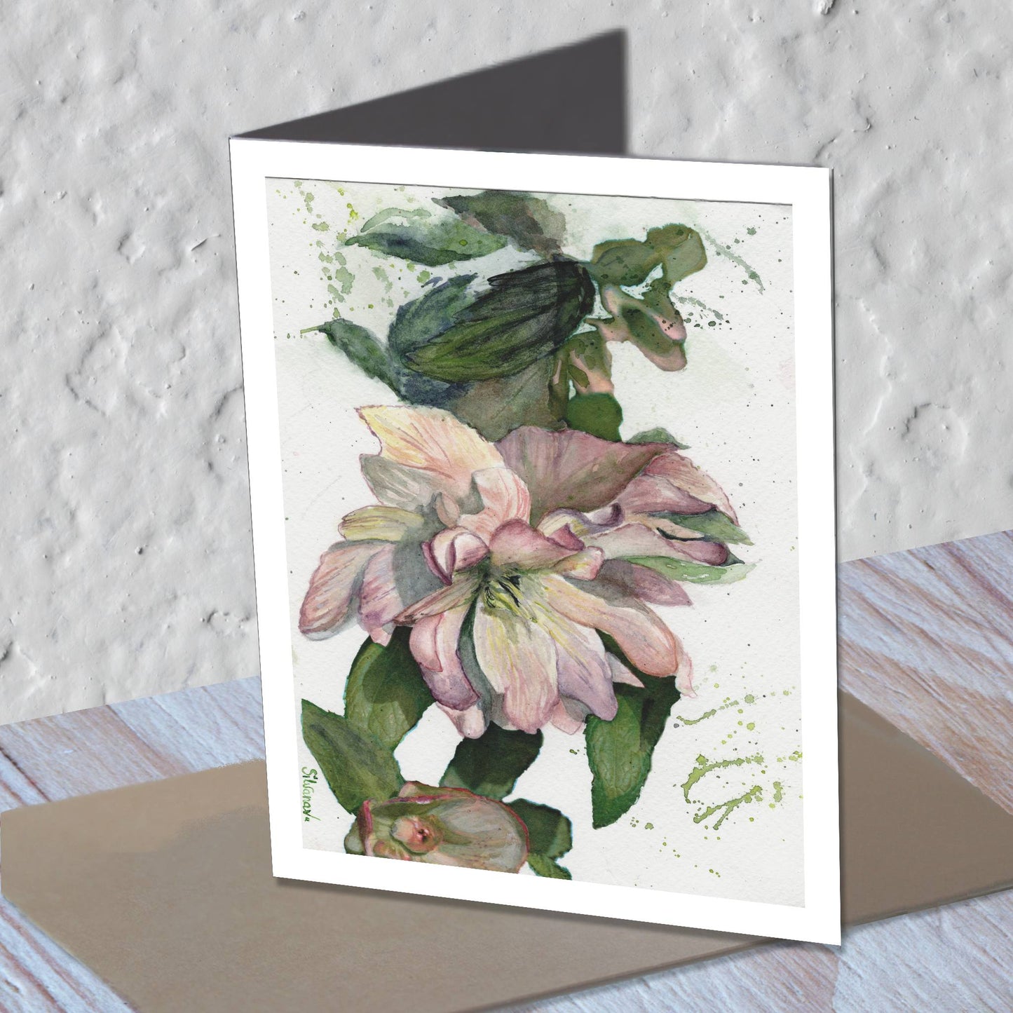 Hellebore watercolor greeting card standing on a kraft envelope.