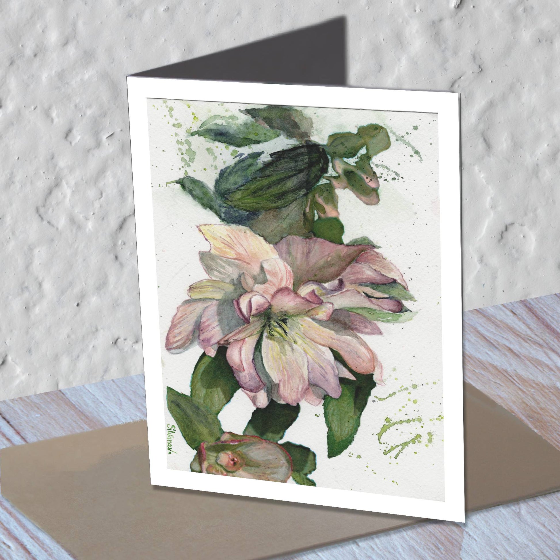 Hellebore watercolor greeting card standing on a kraft envelope.