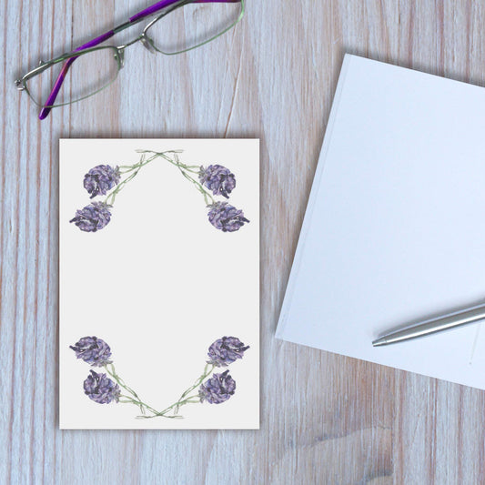 Lavender design notebook closed, with another notebook open beside it, on wooden background.