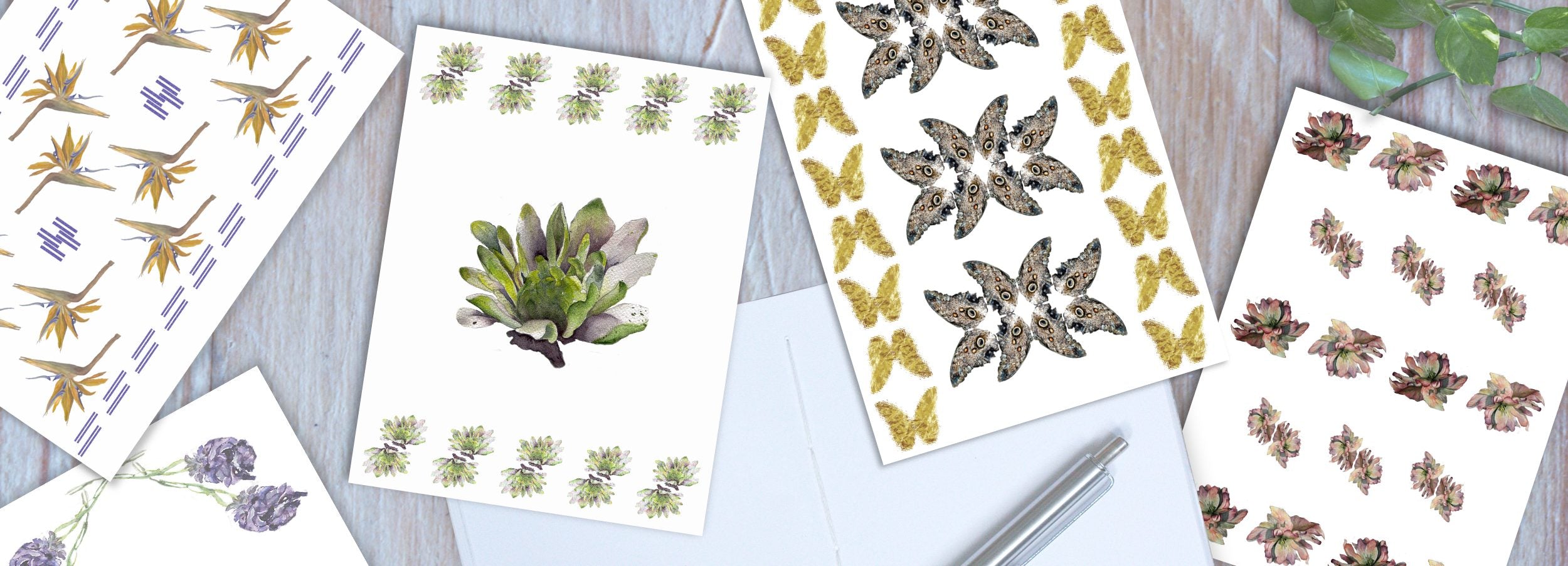 Collection of five original designed notebook covers with one open to show hand-sewn pages and pen on top, fanned out.