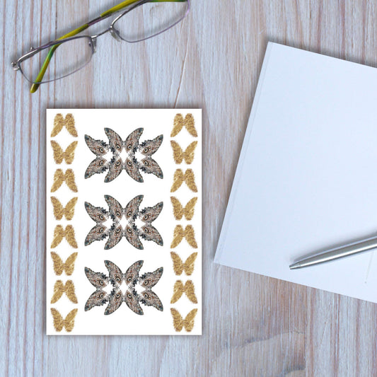 Owl-eye butterfly design notebook closed, with another notebook open beside it, on wooden background.