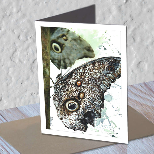 Owl eye butterfly watercolor greeting card standing on a kraft envelope.