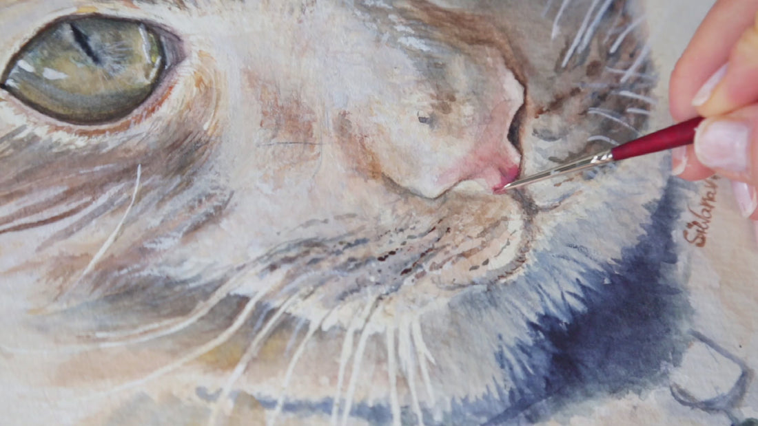 Video showing the artist's hand adding final pink brushstrokes to a cat's nose in a custom watercolor pet portrait, demonstrating the detailed, handmade nature of every commission