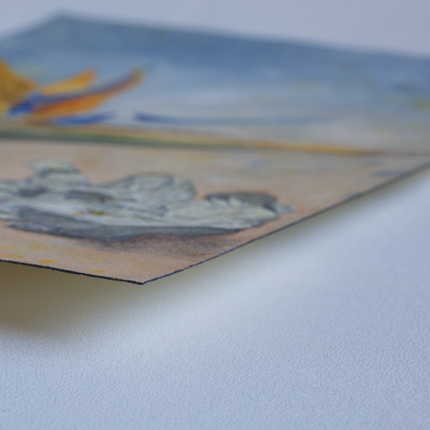 Corner detail of the original watercolor painting Sketching Paradise by Silvana Varriale of VARsee Art, slightly lifted from a flat surface, showing the thickness and texture of professional Arches 100% cotton watercolor paper with its characteristic black edge binding.