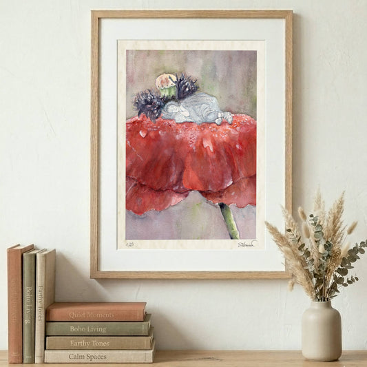 Framed Silvana Varriale watercolor giclée print showing a small figure sleeping on a large red poppy, displayed in a wooden frame on a wall over books and a vase on a shelf. VARsee LLC.