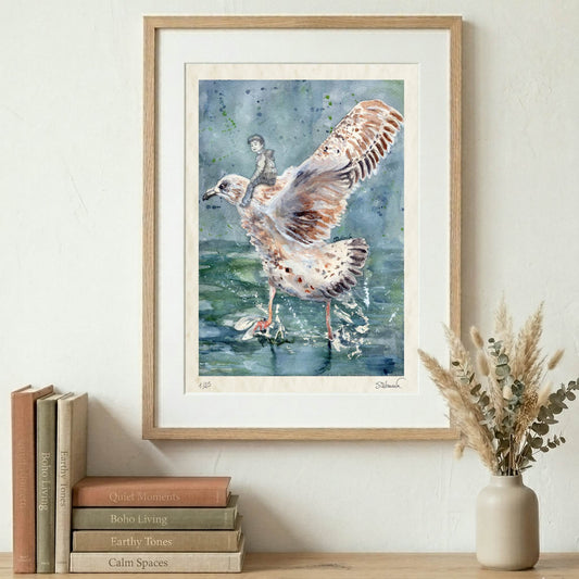 Framed Silvana Varriale watercolor giclée print showing a seagull about to take off from the sea with a small figure sitting on his back. The frame is displayed on a wall over books and a vase on a shelf. VARsee LLC.