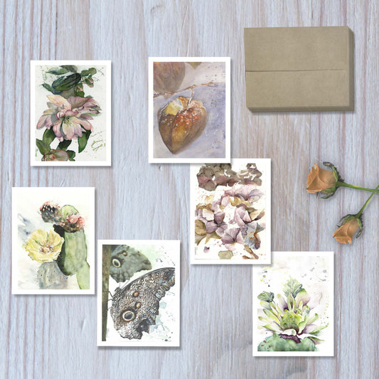 Top view of the earthbound set of 6 botanical watercolor greeting cards, arranged to display each unique design, with six envelopes stacked at the side.