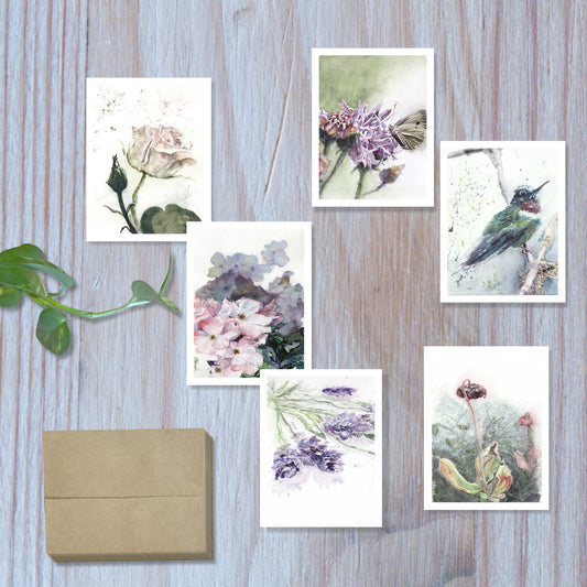 Top view of the violet reverie set of 6 botanical watercolor greeting cards, arranged to display each unique design, with six envelopes stacked at the side.