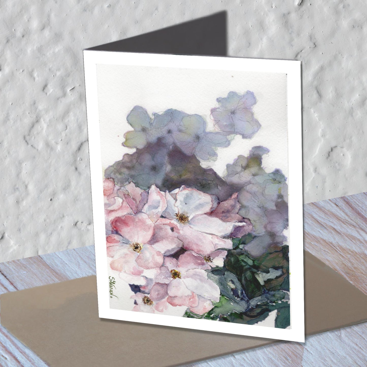 Wild rose rose watercolor greeting card standing on a kraft envelope.